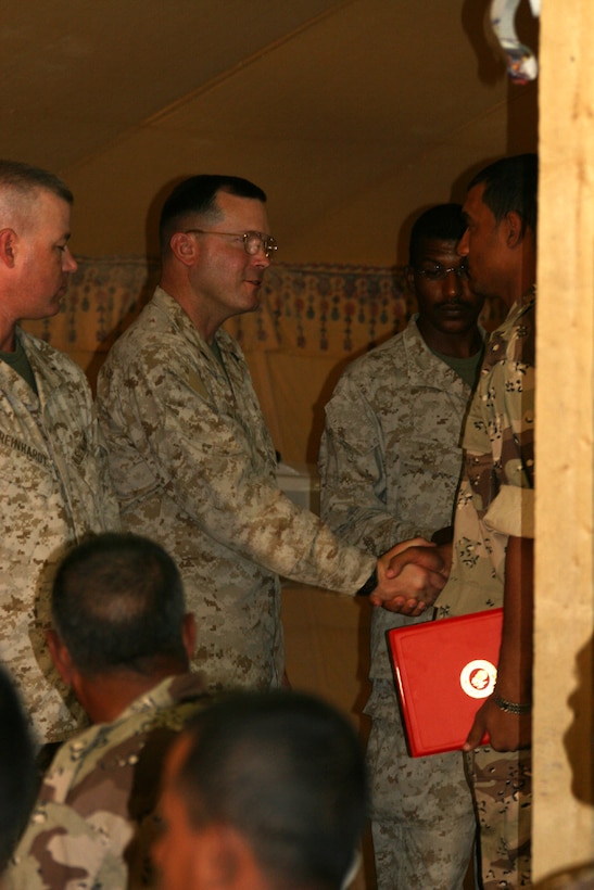 Col. William S. Aitken, the commanding officer of Combat Logistics Battalion 2, congratulates of the Iraq's newest border patrolmen during a class graduation.  Aitken was the guest of honor at the June 27 border patrol graduation and presented the awards and certificates of completion to the men.