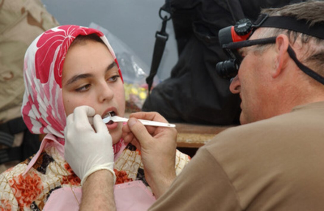 National Guard Maj. Douglas Selbe examines a tooth that is causing pain to an Iraqi girl in Tikrit, Iraq, on June 21, 2005. Medical personnel with Echo Company of the New Jersey National Guard's 50th Main Support Battalion deployed to Forward Operating Base Speicher are providing medical care to residents of Tikrit. 