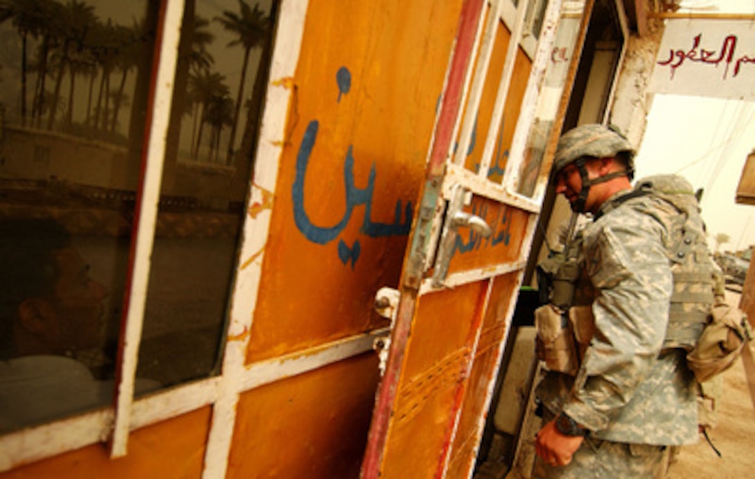 Army Lt. Roy Miller from the 2nd Battalion, 121st Headquarters and Headquarters Company, ducks his head into a shop as he conducts an information operation in a small town near Baghdad, Iraq, on June 23, 2005. 