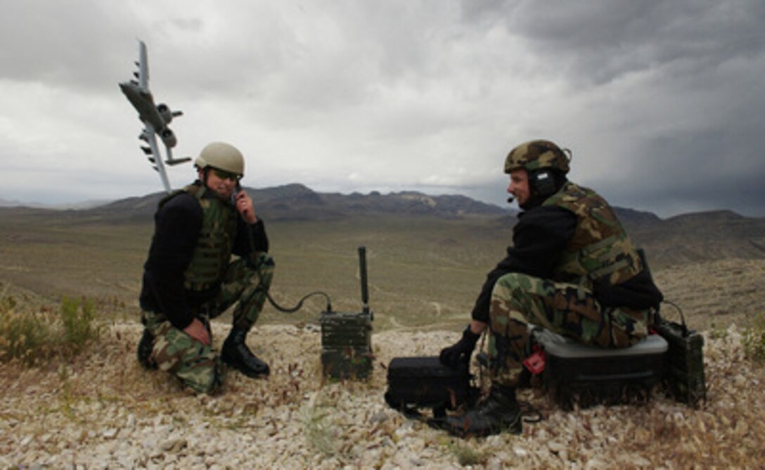 Air Force Tech. Sgt. Robert Mathis (left) works range space issues while Master Sgt. Craig Hillsman gives a "cleared hot" to attack call to an incoming A-10 Thunderbolt II aircraft during a training exercise at the Nevada Test and Training Range on May 22, 2005. Hillsman and Mathis are Joint Terminal Attack Controller Qualification Course instructors with the 6th Combat Training Squadron at Nellis Air Force Base, Nev. The controllers assist ground forces commanders by clearing aircraft to attack authorized targets. 