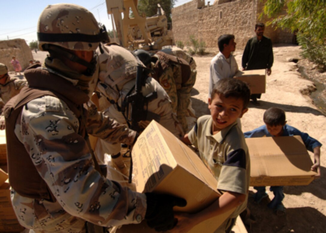 An Iraqi Army soldier hands a box of food to a boy of the Choloq tribe in Um Shababit, Iraq, on June 23, 2005. Soldiers from the Iraqi Army's 3rd Battalion, 4th Company and the U.S. Army's 3rd Armored Cavalry Regiment distributed humanitarian supplies, water and food to members of the tribe. 