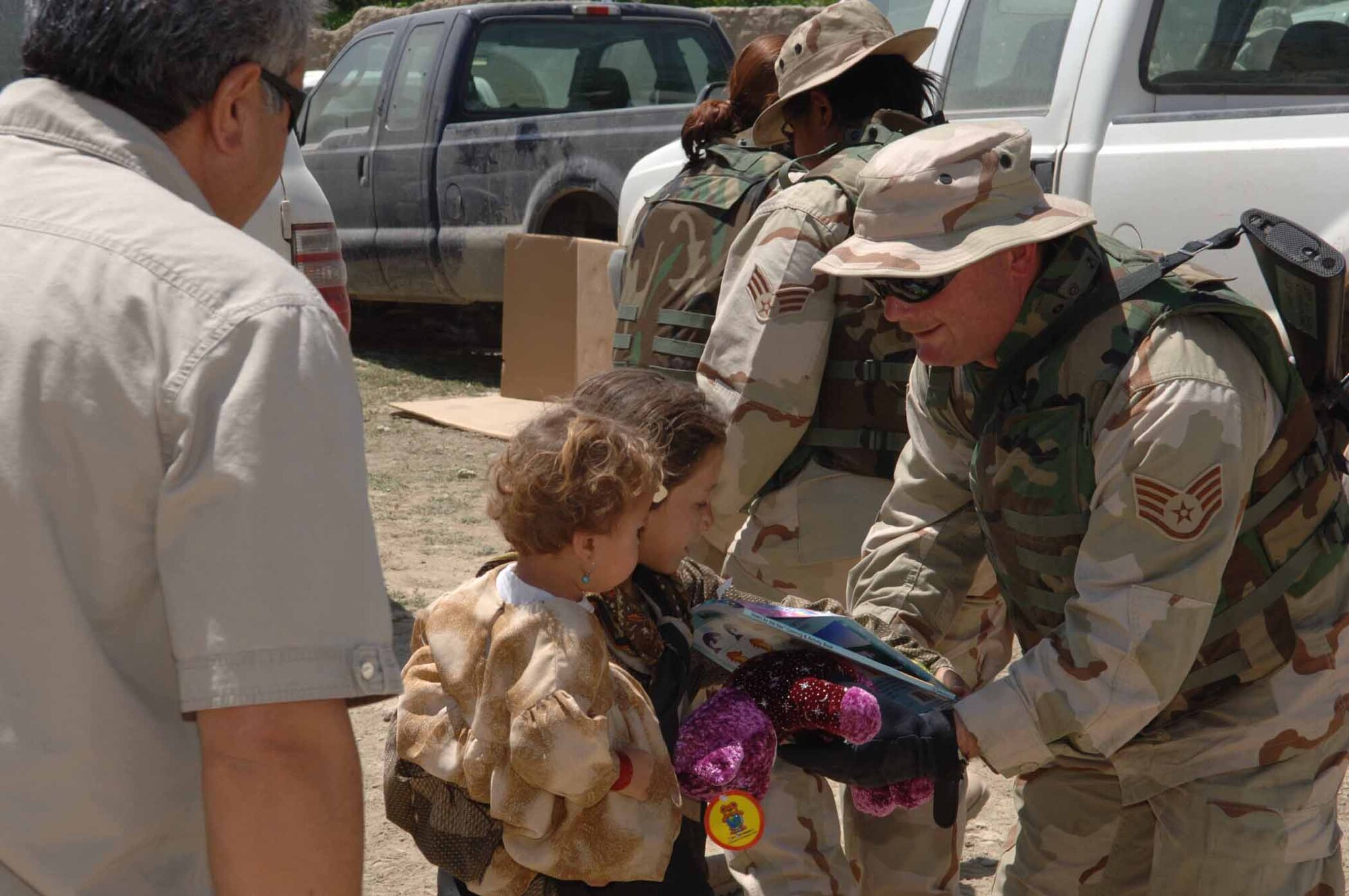 PARWAN PROVINCE, Afghanistan -- Staff Sgt. John Golden hands an Afghan child a stuffed animal and coloring book during an adopt-a-village trip here.  Airmen from the 455th Air Expeditionary Wing at nearby Bagram Air Base take part in the program to assist villages in Afghanistan with infrastructure, fresh water, school supplies and toys for children.  Sergeant Golden is an aerospace ground equipment technician with the 455th Expeditionary Maintenance Squadron and is deployed from Pope Air Force Base, N.C.  (U.S. Air Force photo by Capt. Mark D. Gibson)