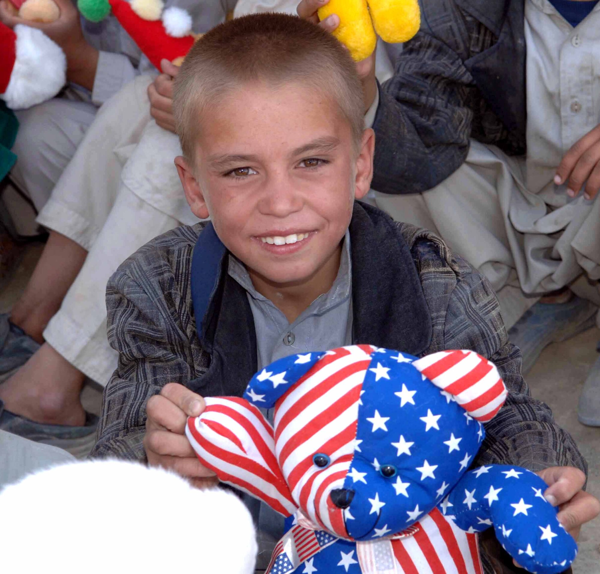 PARWAN PROVINCE, Afghanistan -- An Afghan boy holds up a teddy bear given to him by Airmen of the 455th Air Expeditionary Wing at nearby Bagram Air Base during an adopt-a-village visit.  The program allows Airmen to assist villages in Afghanistan with infrastructure, fresh water, school supplies and toys for children.  (U.S. Air Force photo by Capt. Mark D. Gibson)