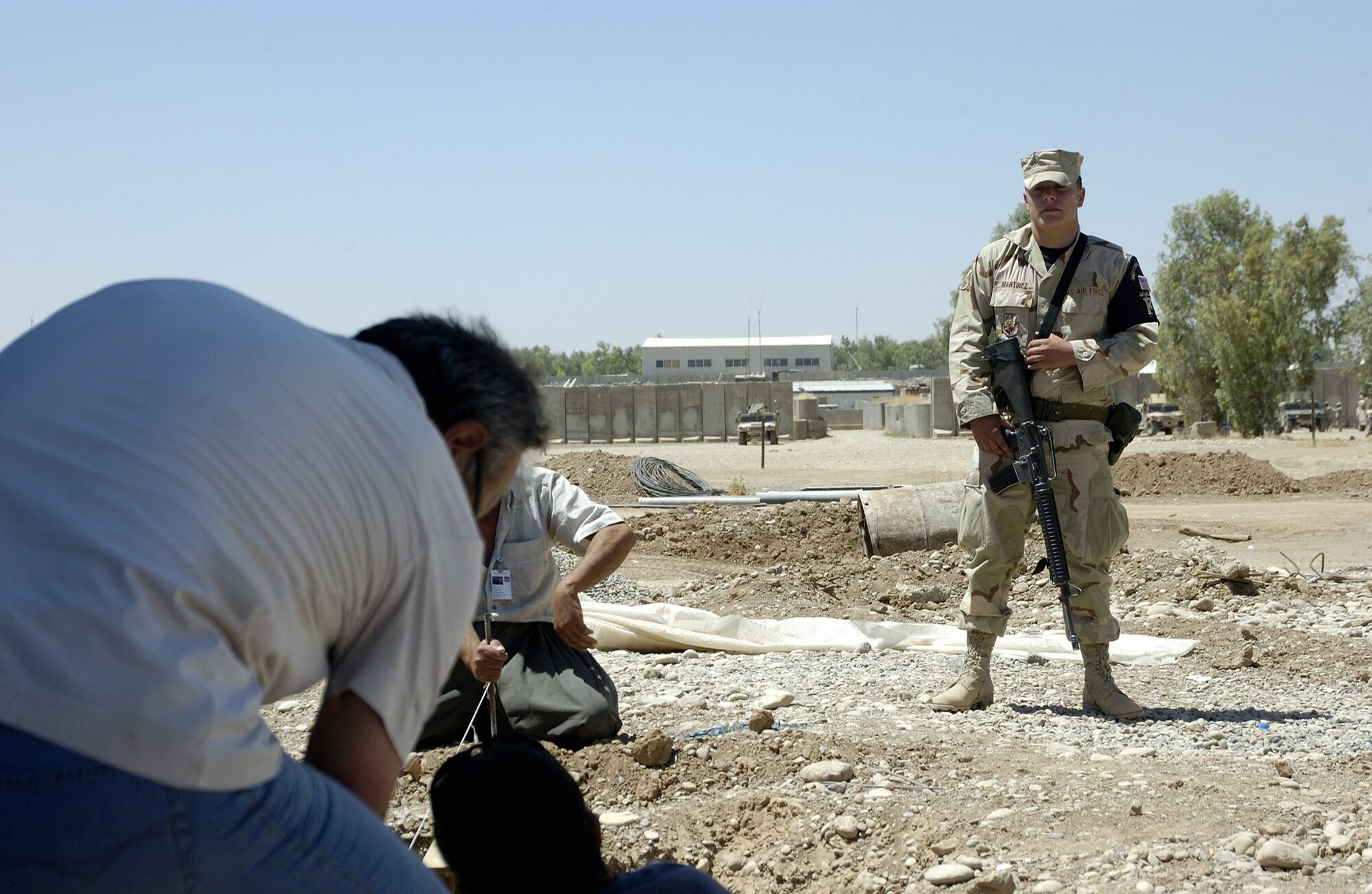 KIRKUK AIR BASE, Iraq -- Senior Airman Donnie Martinez monitors third-country nationals as they construct a building here.  Hundreds of local employees work on the base daily under the watchful eye of escorts.  Airman Martinez is deployed from Lackland Air Force Base, Texas.  (U.S. Air Force photo by Tech. Sgt. Christopher Gish)