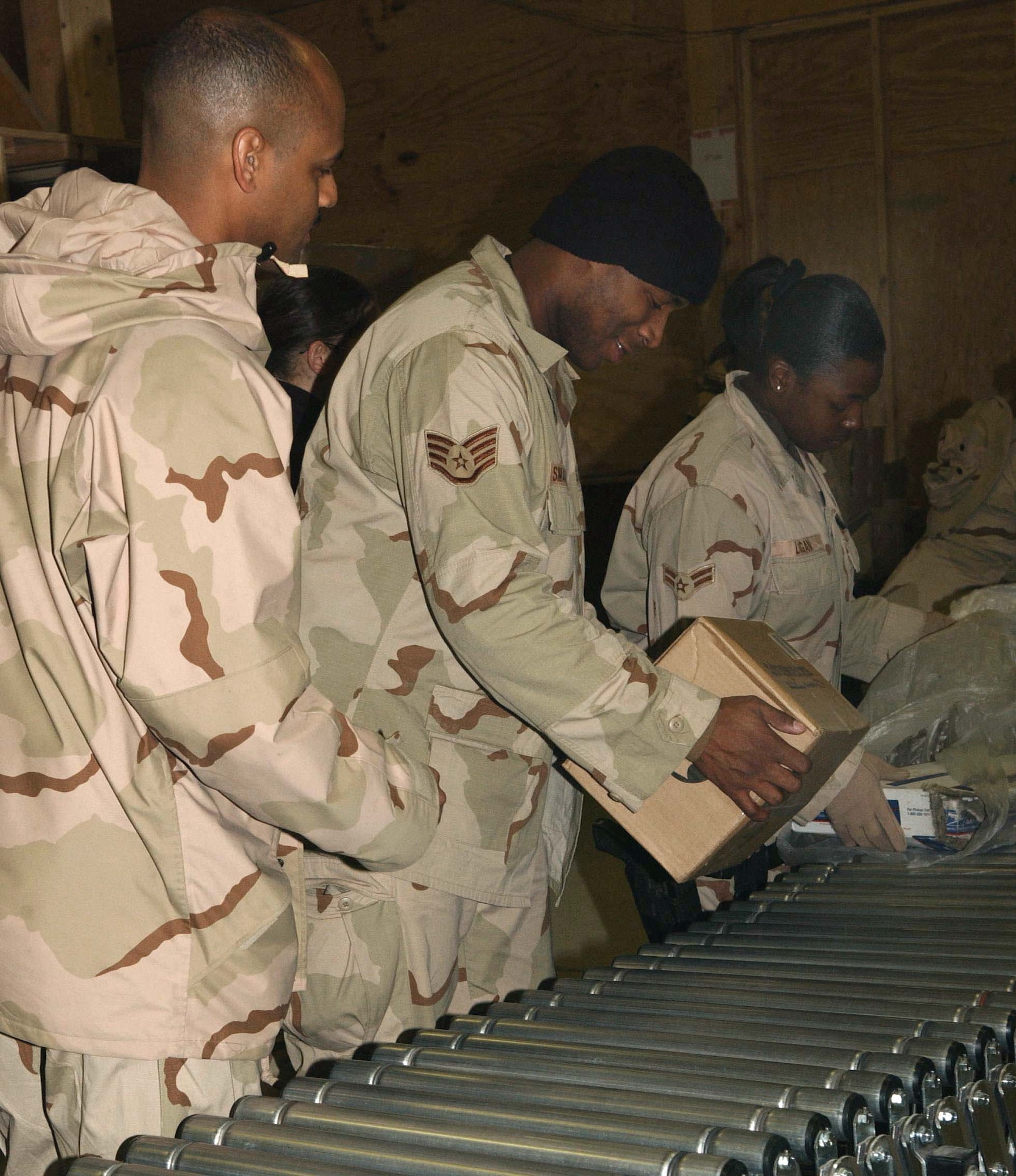 BAGRAM AIR BASE, Afghanistan -- Airmen of the mail team here work together to keep the mail flowing to their fellow servicemembers.  Postal workers process between 15,000 and 50,000 pounds of mail daily.  (U.S. Air Force photo by Capt. Catie Hague)