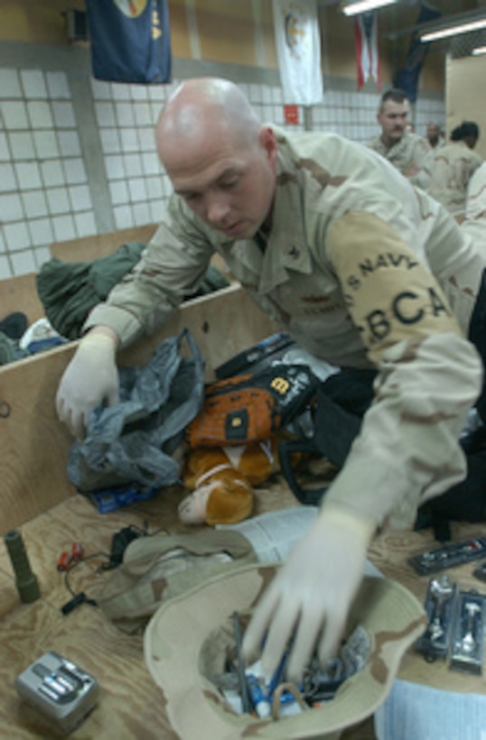 Navy Petty Officer 2nd Class Jeffrey Oberts performs a customs inspection on a U.S. Army soldier's duffle bag at Camp Doha, Kuwait, on March 1, 2005. Oberts is a Navy reservist with Navy Expeditionary Logistics Support Force Forward Oscar, Bravo Company, which is performing the customs mission for the U.S. Army throughout Kuwait and Iraq. 