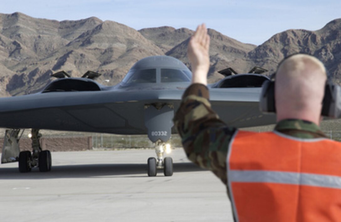 Airman 1st Class Richard Maurer directs the flight crew of a B-2 Spirit to a parking spot on the ramp at Nellis Air Force Base, Nev., on March 1, 2005. The aircraft is participating in Exercise Red Flag at Nellis. Maurer is a crew chief assigned to the 509th Aircraft Maintenance Squadron, deployed from Whiteman Air Force Base, Mo., for the exercise. 