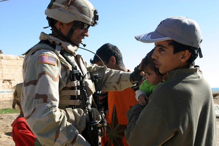 CAMP TAQADDUM, Iraq (March 7, 2005) - Army Sgt. Robert Rodriguez, 2nd Battalion, 112th Armor, 36th Infantry, is greeted by Iraqi children during a civil affairs mission to Al Kabani March 5. The Lorado, Texas, native, and fellow soldiers, along with Marines from the 1st and 2d FSSGs, distributed humanitarian aid supplies and soccer balls to the town of about 60 homes. (Photo by Cpl. John E. Lawson Jr.)
