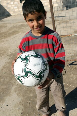 CAMP TAQADDUM, Iraq (March 7, 2005) -An Iraqi child plays with the soccer ball given to him by American service members during a civil affairs mission to Al Kabani March 5. Marines from the 1st and 2d Force Service Support Groups (Forward), and soldiers from the Army's 2nd Battalion, 112th Armor, 36th Infantry, distributed humanitarian aid supplies and soccer balls to the town of about 60 homes. (Photo by Cpl. John E. Lawson Jr.)