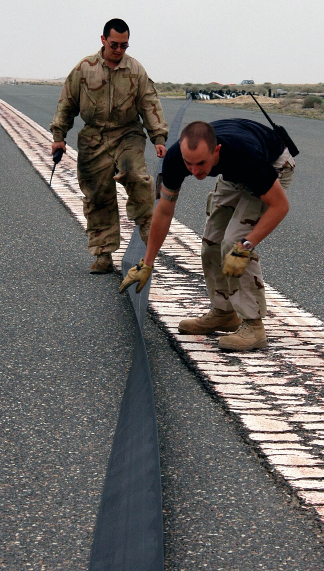 SOUTHWEST ASIA -- Airmen of the 386th Expeditionary Civil Engineer Squadron inspect a mobile aircraft arresting system tape for fraying, tears or any other discrepancy before the system is certified and reeled back in.  (U.S. Air Force photo by Staff Sgt. William Farrow)