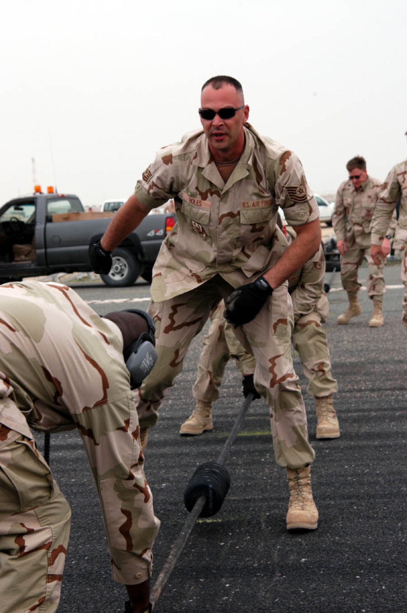 SOUTHWEST ASIA -- Tech. Sgt. Brian Holes gives directions as he assists the power production crew with laying the steel braid cable across the runway, and spreading the &quot;donuts&quot; at six to eight feet apart.  The donuts raise the cable off the ground so the arresting hook can engage the cable.  Sergeant Holes is the 386th Expeditionary Civil Engineer power production flight superintendent.  (U.S. Air Force photo by Staff Sgt. William Farrow)