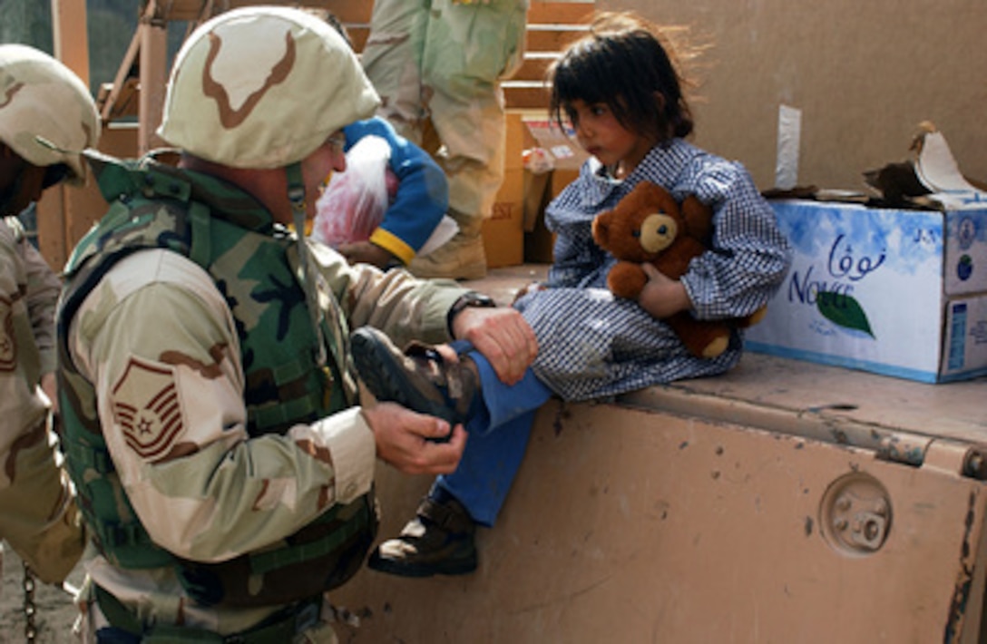 U.S. Air Force Master Sgt. Terry Nelson fits a new pair of shoes on a young Bedouin girl in a village near Tallil Air Base, Iraq, on March 5, 2005. Nelson, from the 388th Fighter Wing, Hill Air Force Base, Utah, is deployed with the 407th Air Expeditionary Group as the Chief of Group Public Affairs. 