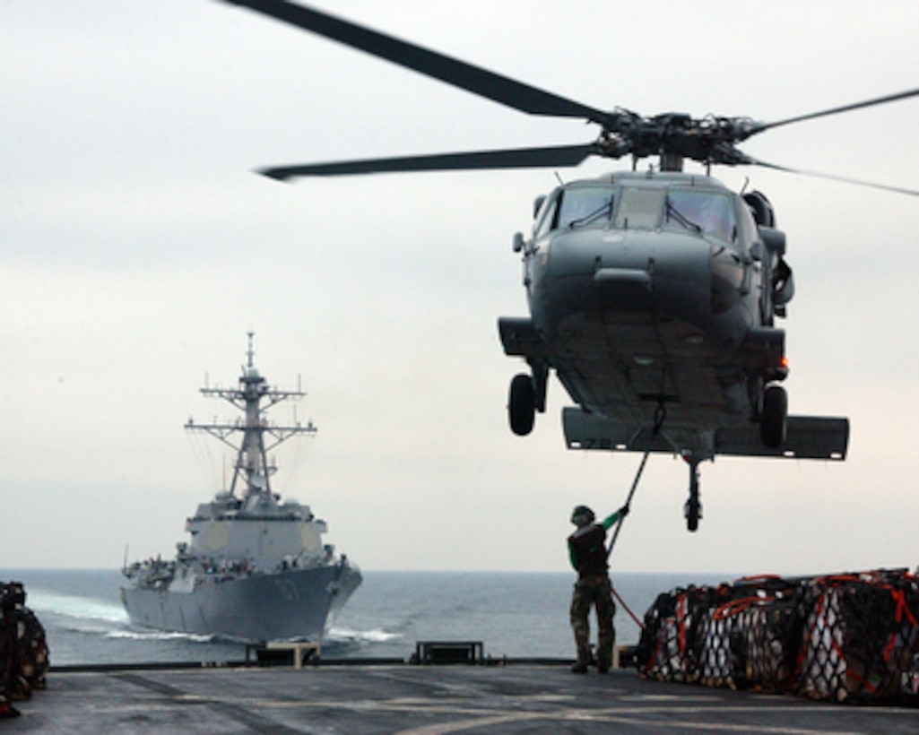 A flight deck crew member aboard the USNS Arctic (T-AOE 8) attaches a cargo pendant onto the hook of an MH-60S Seahawk helicopter during a vertical replenishment with the guided missile destroyer USS Mason (DDG 87) as the ships steam in the Persian Gulf on Feb. 25, 2005. The Artic is a Military Sealift Command fast combat support ship. 