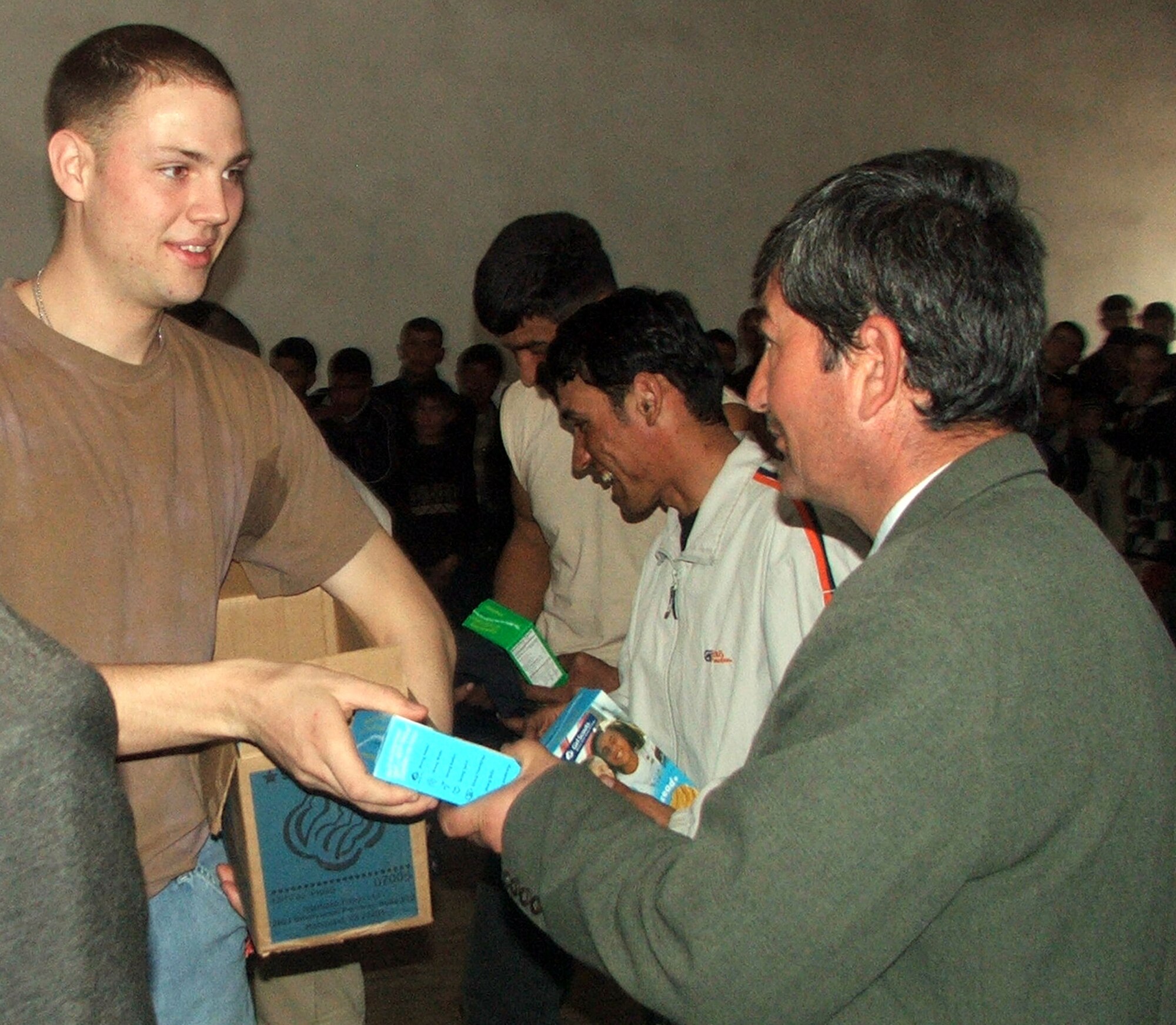 KHANABAD, Uzbekistan -- Senior Airman Jason Yarborough hands a box of cookies to an Uzbek man during a humanitarian aid visit here March 3.  A group of Airmen and Soldiers from nearby Karshi-Khanabad Air Base visited the village medical clinic and the school where they played a volleyball game and handed out donations.  (U.S. Air Force photo by Tech. Sgt. Scott T. Sturkol) 