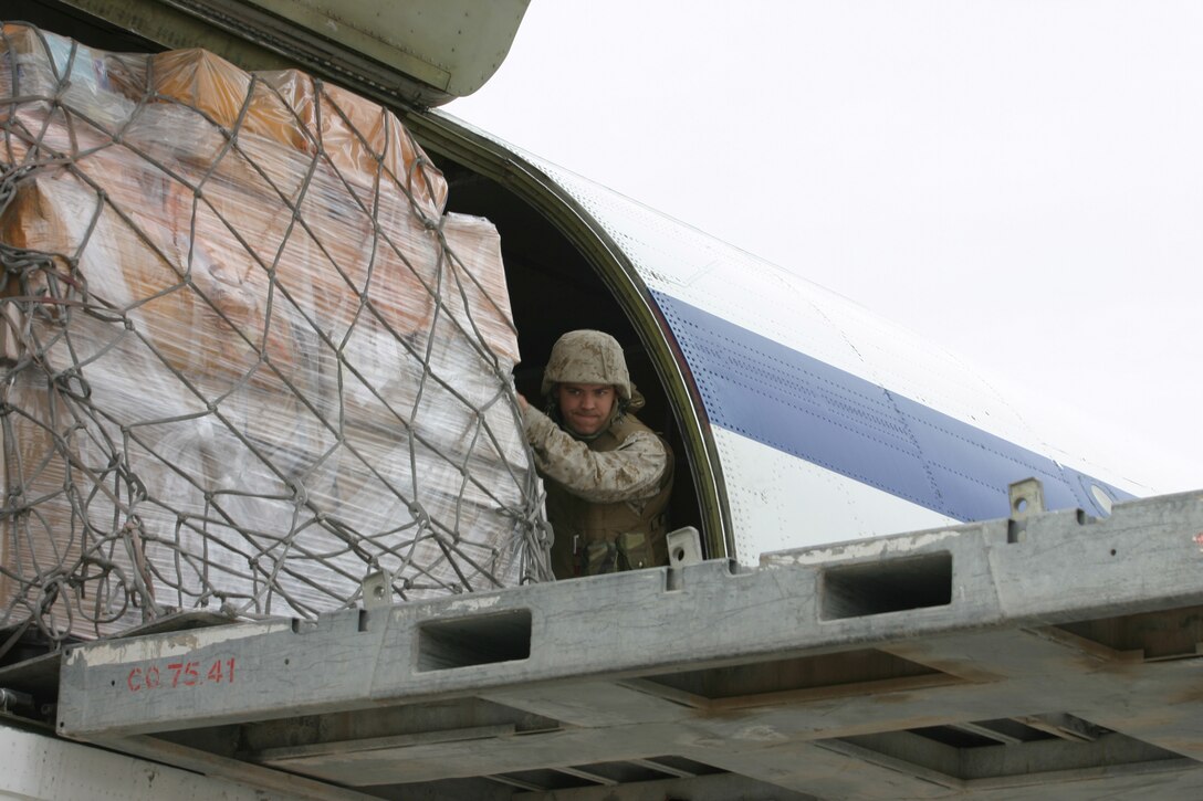 CAMP TAQADDUM, Iraq (March 11, 2005) - Lance Cpl. David A. Sadler, a native of Bourbonnais, Ill., helps unload one of the 14 pallets of mail received here March 9. The 24-year-old 2d Force Service Support Group (Forward) postal clerk is one of 24 Marines who assumed postal responsibilities from 1st FSSG during a mass turn over of troops here in support of Operation Iraqi Freedom. (Photo by Sgt. Kristin S. Jochums)