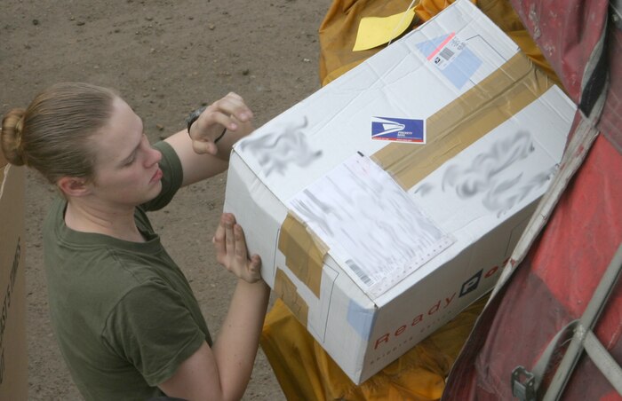 CAMP TAQADDUM, Iraq (March 11, 2005) - Lance Cpl. Dorthea F. Daniels, a native of Jacksonville, N.C., unloads packages from one of the many mail containers they received here March 9. The Marines of 2d Force Service Support Group (Forward) receive 10-18 pallets of mail on a typical day. The 20-year-old 2d FSSG postal clerk is one of 24 Marines who assumed postal responsibilities from 1st FSSG during a mass turn over of troops here in support of Operation Iraqi Freedom. (Photo by Sgt. Kristin S. Jochums)