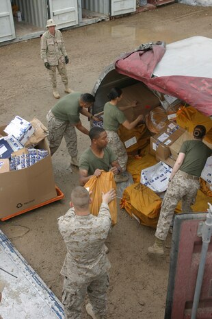 CAMP TAQADDUM, Iraq (March 11, 2005) - Marines with Force Service Support Group (Forward) postal work together to unload one of the many mail containers they received here March 9. The postal clerks receive 10-18 pallets of mail on a typical day. Their mission is to route the letters and packages to the thousands of service members serving throughout western Iraq. (Photo by Sgt. Kristin S. Jochums)