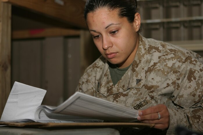 CAMP TAQADDUM, Iraq (March 11, 2005) - Lance Cpl. Kelly A. Martinez, a native of Hammond, Ind., looks through a list of all the units throughout Iraq to route mail and packages to deployed service members. The 24-year-old 2d Force Service Support Group (Forward) postal clerk is one of 24 Marines who assumed postal responsibilities from 1st FSSG during a mass turn over of troops here in support of Operation Iraqi Freedom. (Photo by Sgt. Kristin S. Jochums)