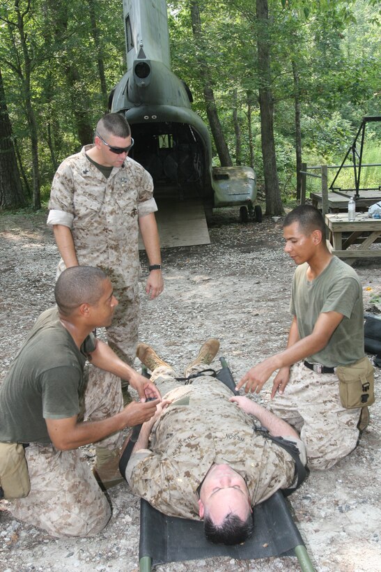 Petty Officers 3rd Class Edwin Bringner (lower left) and Rene Nava (kneeling on the right), company corpsmen with Weapons Company,  3rd Battalion, 23rd Marine Regiment, 4th Marine Division, currently attached to 8th Marine Regiment, 2nd Marine Division, work on Lt. Cmdr. Michael Wilson (on the litter), the assistant battalion surgeon, as they explain what injuries the casualty has and how they treated him to Petty Officer 1st Class Brian Gerdes, the leading petty officer with Special Operations Training Group, II Marine Expeditionary Force, as part of patient-care and casualty-evacuation sustainment training here Aug. 9. The training was preparation for Marine Corps Air Ground Combat Center Twentynine Palms, Calif., exercise Mojave Viper where the corpsmen will do intensive casualty-evacuation training.
