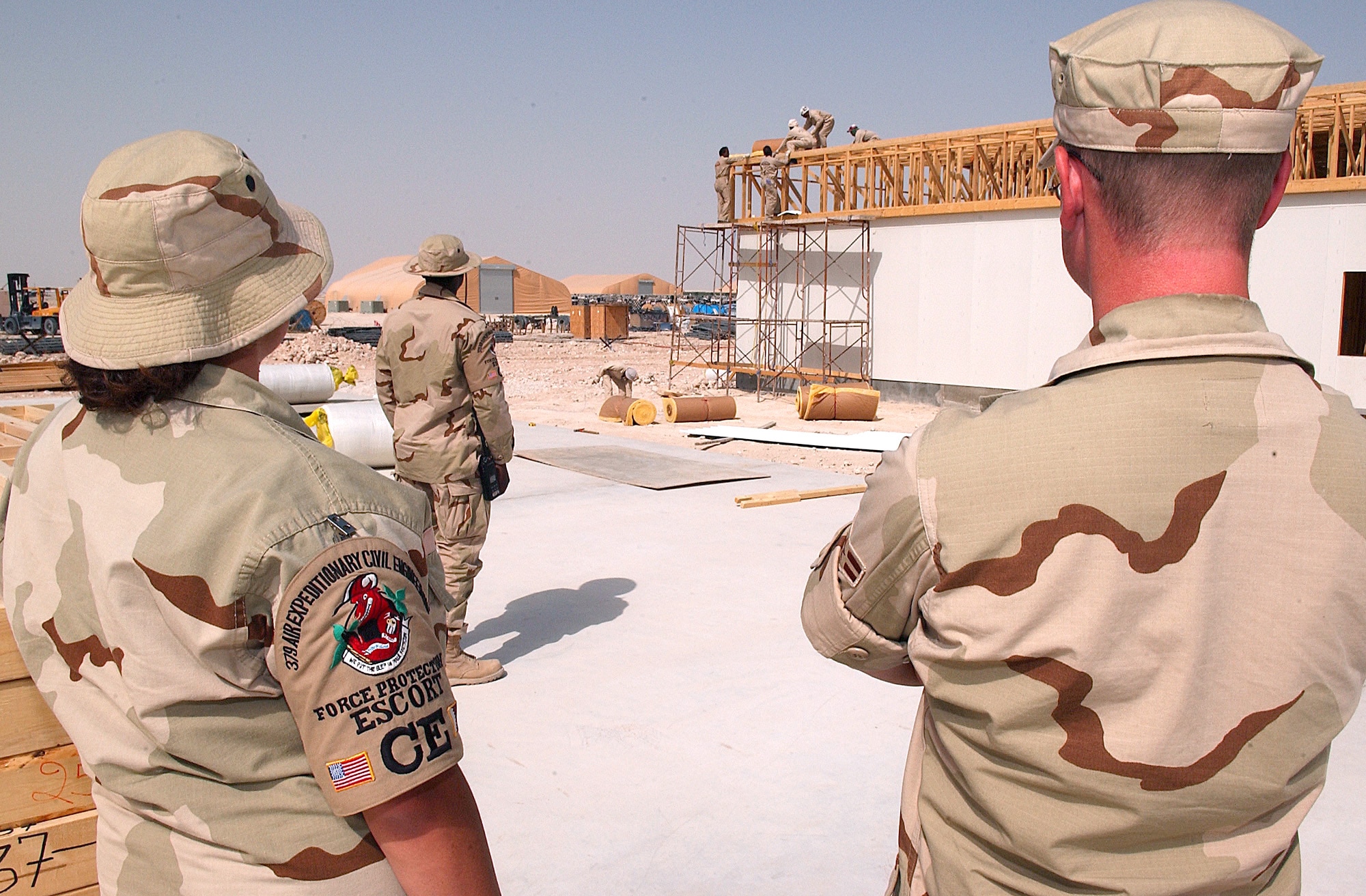 SOUTHWEST ASIA -- Escorts assigned to the 379th Expeditionary Civil Engineer Squadron observe foreign workers at a base construction site.  (U.S. Air Force photo by Staff Sgt. Colette Bennett)