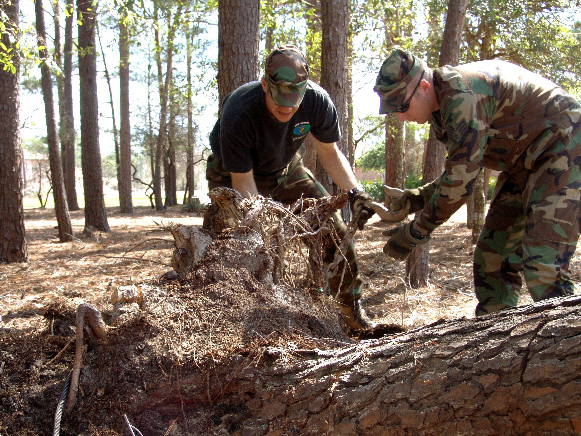 SHALIMAR, Fla. -- Staff Sgts. Jon Farr (left) and Andrew Shone hook the wench of a five-ton truck to a stump.  The Airmen and other instructors with the 96th Ground Combat Training Squadron at nearby Eglin Air Force Base cut up fallen trees and pulled 18 stumps, saving the village more than $2,000.  Hurricane Ivan downed hundreds of trees on the property and caused more than $300,000 in damage.  (U.S. Air Force photo by Senior Airman Mike Meares)
