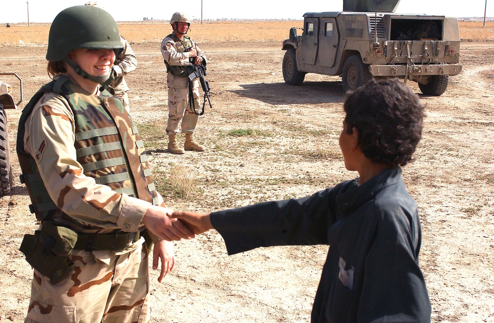 NEAR TALLIL AIR BASE, Iraq -- Airman 1st Class Jessica Farley meets a child here during a visit to a Bedouin camp as part of an outreach program as Tech. Sgt. Richard Shinn provides security.  Airman Farley is assigned to the 407th Expeditionary Services Squadron, and Sergeant Shinn is assigned to the 407th Security Forces Squadron.  (U.S. Air Force photo by Master Sgt. Mark Bucher) 