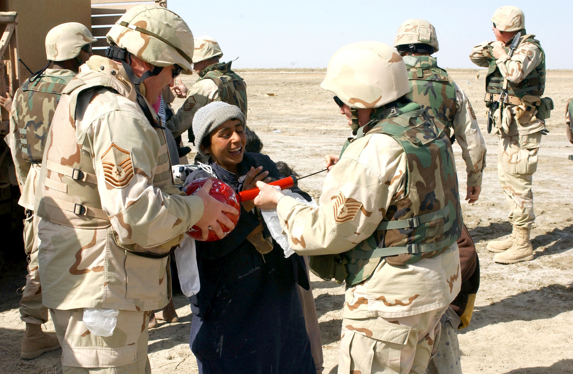 NEAR TALLIL AIR BASE, Iraq -- Master Sgt. Paul Booton (left) and Tech. Sgt. Kimberly Justice help inflate a soccer ball for a child here during a visit to a Bedouin camp as part of an outreach program.  The Airmen are assigned to the 407th Expeditionary Logistics Readiness Squadron.  (U.S. Air Force photo by Master Sgt. Mark Bucher)   