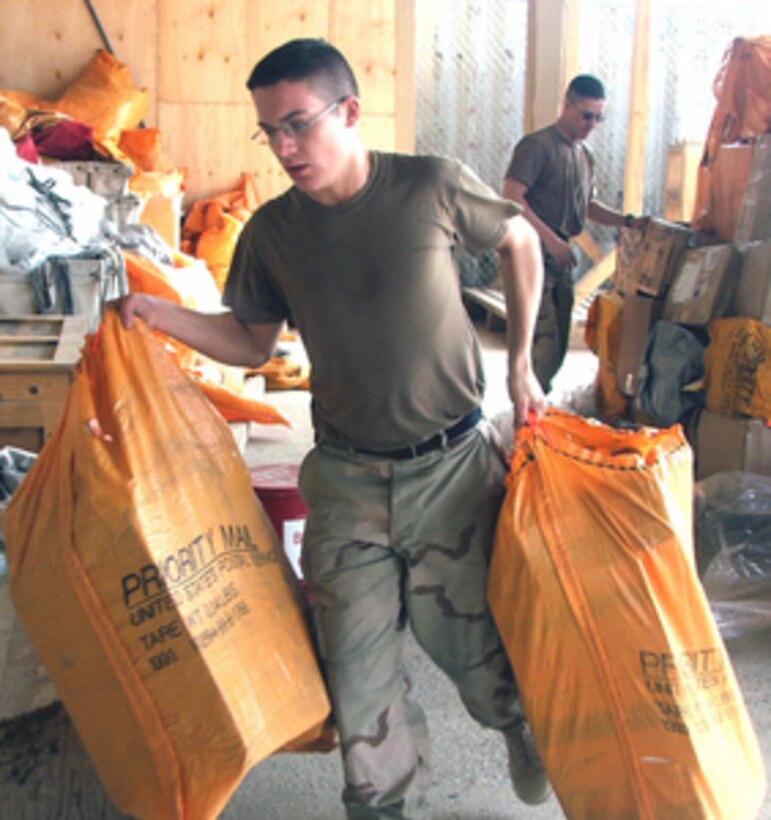 U.S. Army Pfc. Bruce Downard carries bags of mail from a mail pallet at Karsh-Khanabad Air Base, Uzbekistan, on March 6, 2005. The mail will be sorted and forwarded to troops deployed throughout Southwest Asia. Downard is a finance clerk for the 841st Postal Company. 