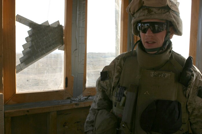 CAMP TAQADDUM, Iraq - Private First Class John Super, an ammunition technician, from Kansas City, Kansas, mans an observation post along the edge of the base here. Super, 28, volunteered to deploy to Iraq with his reserve unit, general support ammunition platoon, Ammunition Company, 4th Supply Battalion, 4th Force Service Support Group from Topeka, Kansas, but never thought he would find himself standing watch over the barren landscape of Iraq. Super is assigned to the Provisional Rifle Company, Headquarters and Service Bn., 2d Marine Logistics Brigade (Forward), based out of Camp Lejeune, N.C. (Photo by Cpl. C.J. Yard)