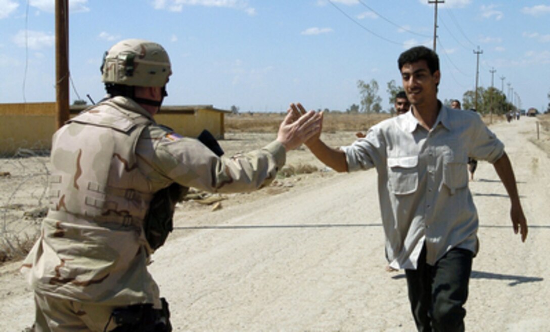 Army Staff Sgt. Thomas Lakes gives an Iraqi Police Force candidate a high five as he completes the running event during a physical fitness test at Camp Echo, Dawanyah, Iraq, on March 13, 2005. The fitness test is a part of screening process for recruitment into the Iraqi Police Force. Lakes is attached to the 940th Military Police Company out of Walton, Ky. 