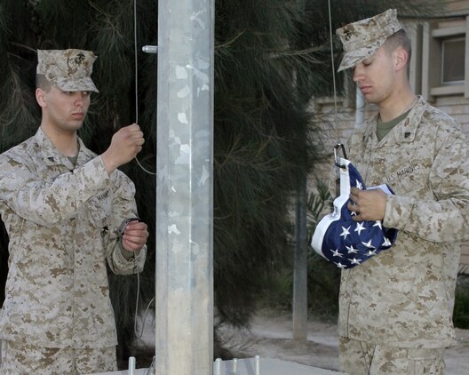 March 17, 2005, Corporal Daniel J. Patron (left) and Sergeant Colin M. Martin, both from the 2d Marine Aircraft Wing Band, retire the United States colors for the evening on airstation Al Asad, Iraq.(USMC photo by Cpl. Alicia M. Garcia)