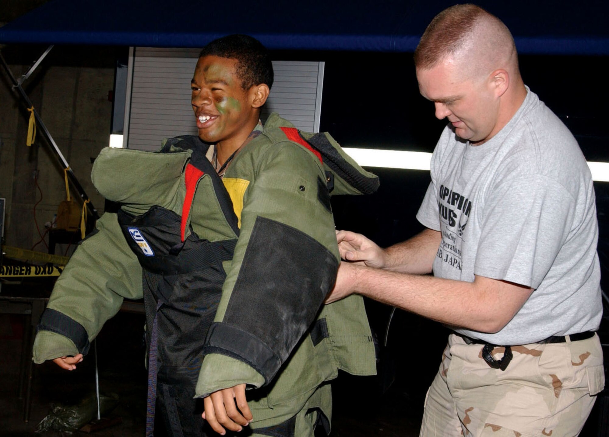 KADENA AIR BASE, Japan -- Staff Sgt. David Baker (right) helps Jeffery Gary put on protective gear for disarming a bomb as part of an Operation Kids Understanding Deployment Operations event March 12.  More than 320 children participated in the event to learn more about how their military parents deploy.  Sergeant Baker is an explosive ordnance disposal technician with the 18th Civil Engineer Squadron.  Jeffery is the son of Master Sgt. Kevin Gary of the 18th Equipment Maintenance Squadron. (U.S. Air Force photo by Senior Airman Mercedes McAlister)