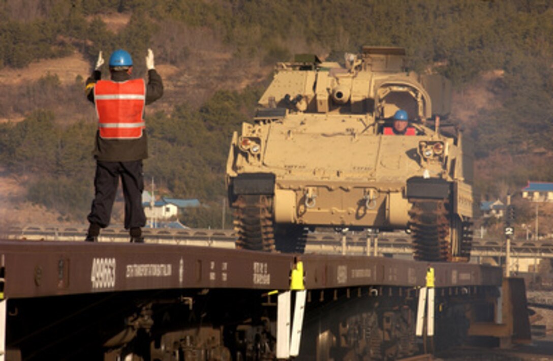 A Korean contractor directs the driver of an U.S. Army M577 Command Post Carrier onto a flatbed railroad car during exercises Reception, Staging, Onward movement, and Integration/Foal Eagle at the Gwangyang Port Terminal, Republic of Korea, on March 14, 2005. The annual, multi-phase exercise is tailored to train, test, and demonstrate U.S. and Republic of Korea force projection and deployment capabilities. 