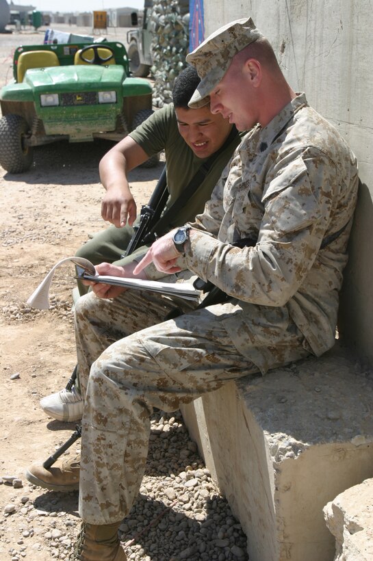 Sgt. Brandon S. Frakes, headquarters communication technical chief, and Lance Cpl. Gabriel Manzo look over the list of runners participating in the Lt. Col. Kevin M. Shea memorial run.  The run honored the Marines of Regimental Communication Team One who died while stationed at Camp Fallujah.