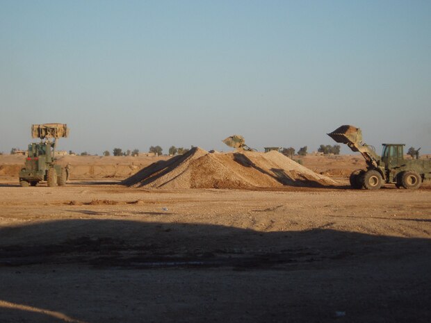 Iraq -- Marines operating a tractor rubber-tired articulated-steering multi-purpose loaders, prepare to load dump trucks during Operation Bedrock.  A joint effort between the Army, Seabees and Marines from heavy equipment platoon, 8th Engineer Support Battalion, 2d Force Service Support Group (Forward).  The service members harvested 3,800 cubic yards of gravel during the operation.  The service members spent five of six nights in the field to get the TRAMs up and running to ensure timeliness of the operation.