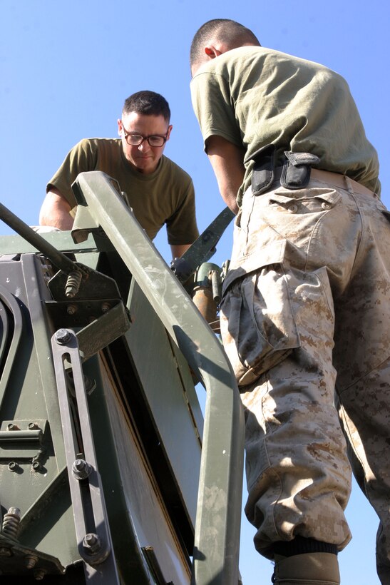 Lance Cpls. Jesus S. Rubalcava (left), 23, a native of Pacoma, Calif., and Anthony J. Asmar, 21, a native of Detroit, check the mobility of a turret recently installed on a 7-ton truck. The Marines, both Logistics Vehicle Operators with MEU Service Support Group 15, are in Iraq conducting security and stability operations with their unit.