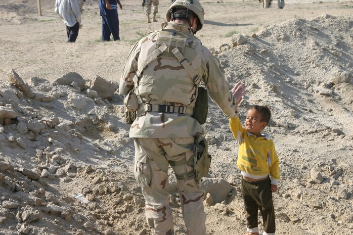 CAMP TAQADDUM, Iraq (March 29, 2005) - A soldier 'high-fives' a local Iraqi boy during one of the visits to the village. Soldiers from 2nd Battalion, 112th Armor, 36th Infantry Division, along with 2d Force Service Support Group (Forward) Marines visit the local villages of Al Kabani and Quiadisisya to hand out soccer balls and backpacks filled with school supplies. Along with the humanitarian visits, contracts for water towers, septic filtration systems and mosque improvements were agreed upon between the village sheiks and the 2/112th. (Photo by Sgt. Kristin S. Jochums)