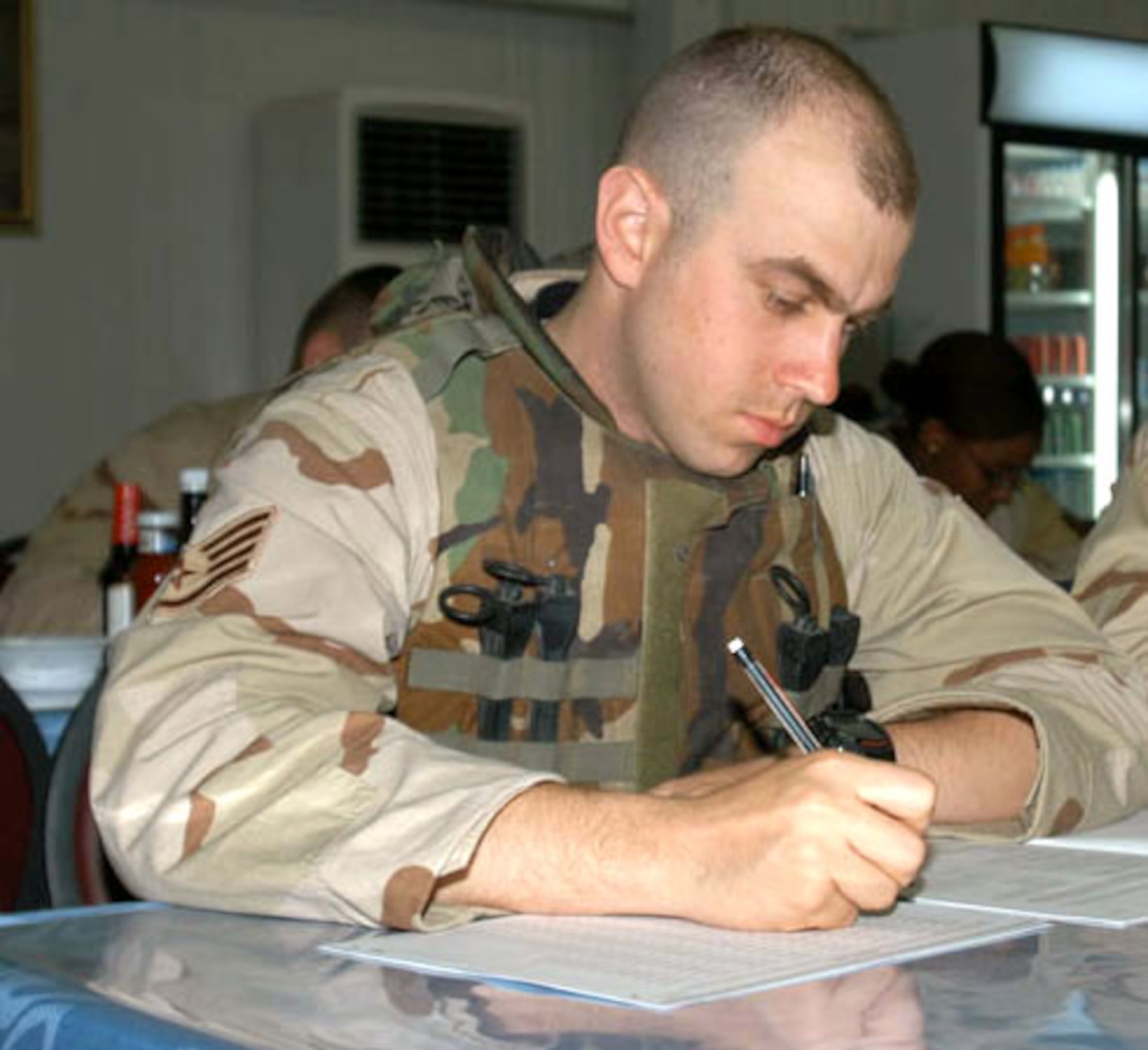 CAMP BUCCA, Iraq -- Still wearing body armor, Staff Sgt. Shawn Andrews answers questions on a College Level Examination Program test here.  Sergeant Andrews was one of 74 Airmen of the 586th Expeditionary Security Forces Squadron taking advantage of a recent visit to the camp by Staff Sgt. Alan Smith, 386th Air Expeditionary Wing test control officer.  Unit members were able to take tests under either the CLEP or Defense Activity for Non-Traditional Education Support programs.  Sergeant Andrews is currently deployed to the 586th Expeditionary Security Forces Squadron here from the 31st Security Forces Squadron at Aviano Air Base, Italy.   (Courtesy photo)