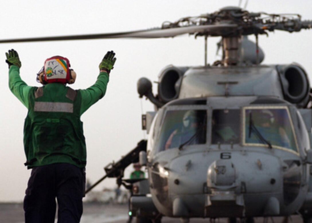 A flight deck crewman signals the pilots of an SH-60 Seahawk helicopter as they prepare to lift off from the aircraft carrier USS Harry S. Truman (CVN 75) on March 10, 2005. The Truman Strike Group and Carrier Air Wing 3 are conducting close air support, intelligence, surveillance, and reconnaissance missions over Iraq. 
