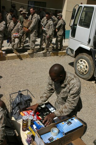 AL ASAD, Iraq (March 25, 2005) - Sergeant Richard W. Dowie, a retail manager with Headquarters and Service Battalion, 2d Marine Logistics brigade (Forward), checks out one of his about 200 customers during a Warfighter Express Services Team operation in Hit, Iraq, March 23. WES Teams bring exchange, postal and disbursing services to service members stationed in the remote regions of Iraq where such services are not normally available. (Photo by: Cpl. John E. Lawson Jr.)