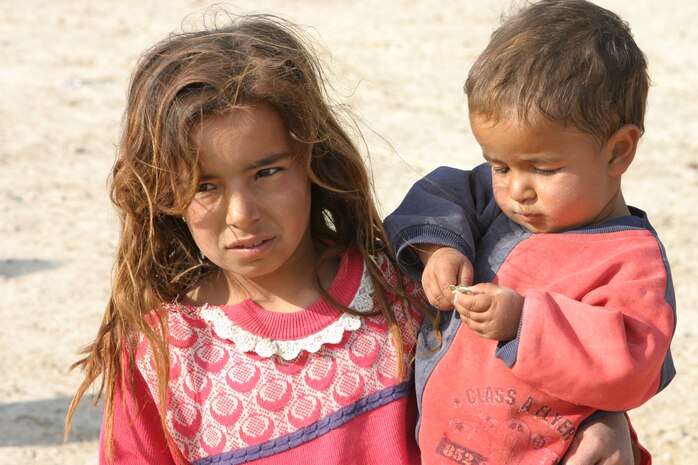 CAMP TAQADDUM, Iraq (March 29, 2005) - An Iraqi girl holds her brother to keep an eye on him while service members visit her village. The 2d Force Service Support Group (Forward) Marines, along with Soldiers from 2nd Battalion, 112th Armor, 36th Infantry Division visit the local villages of Al Kabani and Quiadisisya to hand out soccer balls and backpacks filled with school supplies. Along with the humanitarian visits, contracts for water towers, septic filtration systems and mosque improvements were agreed upon between the village sheiks and the 2/112th. (Photo by Sgt. Krisitn S. Jochums)