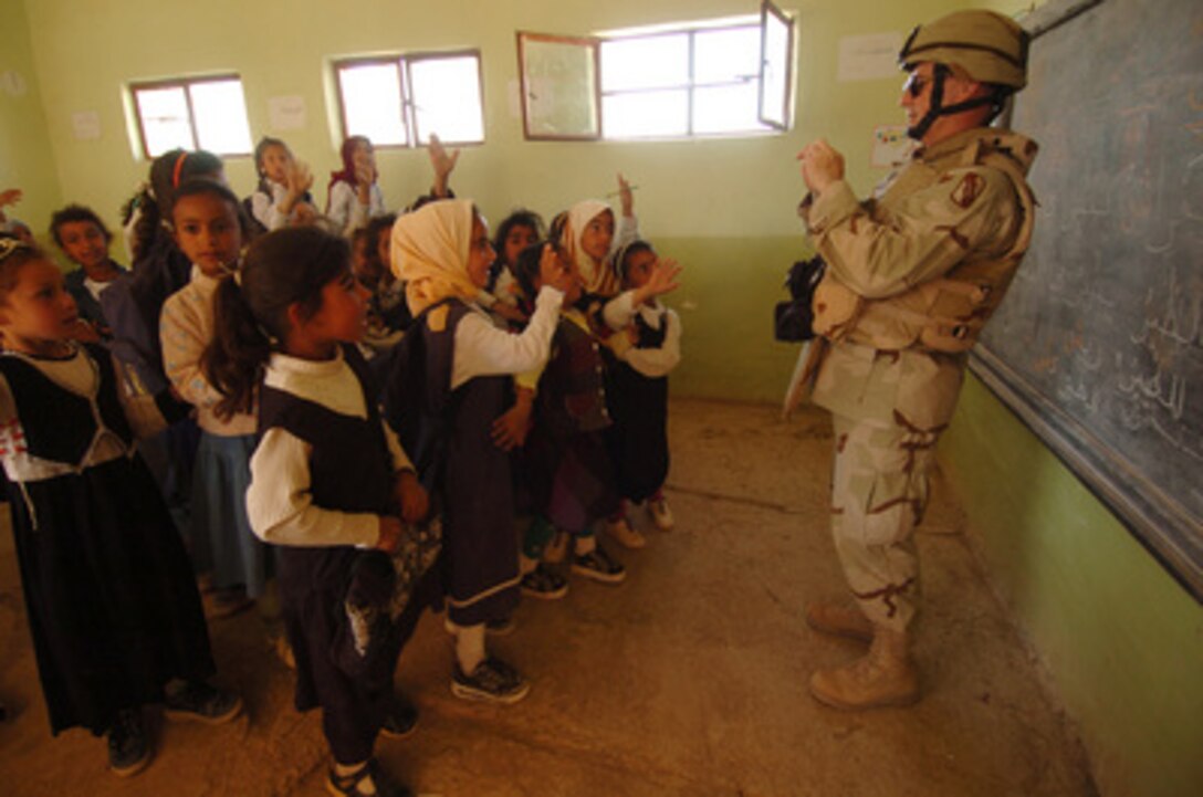 U.S. Army Chaplin Tommy Fuller takes a photo of Iraqi school children at the Al Mutnba Primary School located near Camp Kalsu, Iraq, on March 22, 2005. Members of the155th Brigade Combat Team from Tupelo, Miss., are delivering school supplies under a Fuller-initiated Adopt a School program aboard Camp Kalsu where different units choose a local school and try to connect them with a U.S. school to help with supplies and start a pen pal program. 