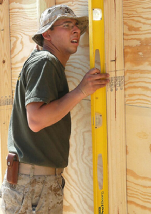 U.S. Marine Cpl. Duran ensures a wall is plumb before it is nailed down to the floor of a building being constructed in Al Taqaddum, Iraq, on March 19, 2005. Duran is attached to the 371st Combat Engineers, Marine Wing Support Squadron 371, which is building the structure for use by Marine Light Attack Helicopter Squadron 775. 