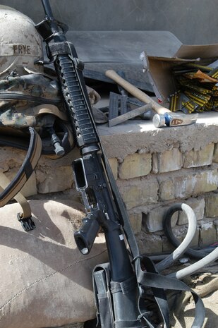 CAMP TAQADDUM, Iraq -- A rifle, kevlar helmet, hammer, nails and square that belong to Cpl. Chase Frye, team leader of a seven-man team of combat engineers from 8th Engineer Support Battalion, 2d Force Service Support Group (Forward), are set down before the Marines begin construction on a Southwest Asia hut.  Frye, who hails from Columbia, S.C., has aspirations of taking over his uncle's construction business after his contract with the Marine Corps expires.