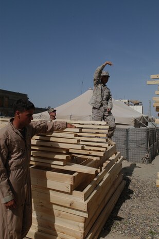 CAMP TAQADDUM, Iraq --Lance Cpl. Anouphong Chanthamany, a combat engineer with 8th Engineer Support Battalion, 2d Force Service Support Group (Forward), directs a forklift operator dropping off materials for building Southwest Asia huts.  Chanthamany, a Milwaukee native, is part of a seven-man team of combat engineers who construct Southwest Asia huts and office spaces for the service members of the base.