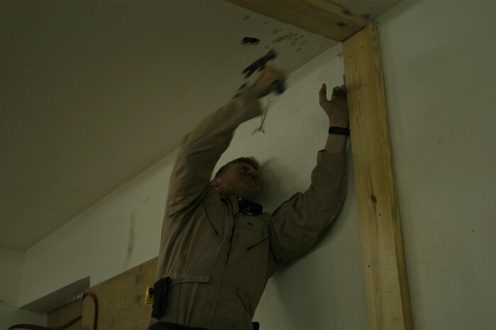 CAMP TAQADDUM, Iraq --Corporal Chase Frye, a combat engineer with 8th Engineer Support Battalion, 2d Force Service Support Group (Forward), pounds a two-by-six.  Frye, a native of Columbia, S.C., is the team leader of a seven-man team of combat engineers who construct Southwest Asia huts and office spaces for the service members of the base.