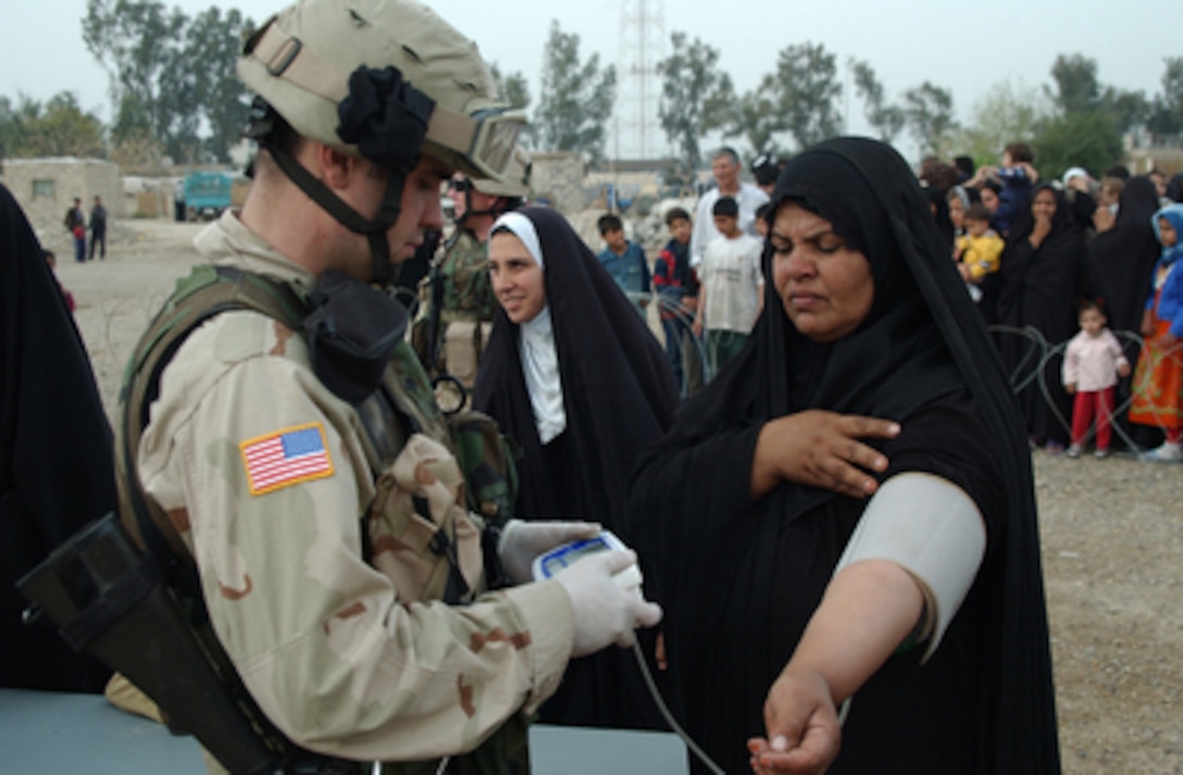 Army Medic Spc. James Hanson takes the blood pressure of a woman in the Janain neighborhood of the Karkh district, located in Baghdad province, prior to her seeing a doctor at an improvised health clinic in Iraq on March 9, 2005. Hanson is attached to the 4th Brigade, 64th Armor Regiment, 3rd Infantry Division. 