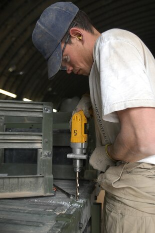 CAMP TAQADDUM, Iraq -- Jim Edmonds, a Honeywell contractor, drills holes for the locking mechanisms on the back of a troop and cargo carrier humvee.  The Marine Armor Kits have combinations of one-quarter inch high-hard steel, three-eighths inch rolled homogenous armor and mild steel to offer improved protection.