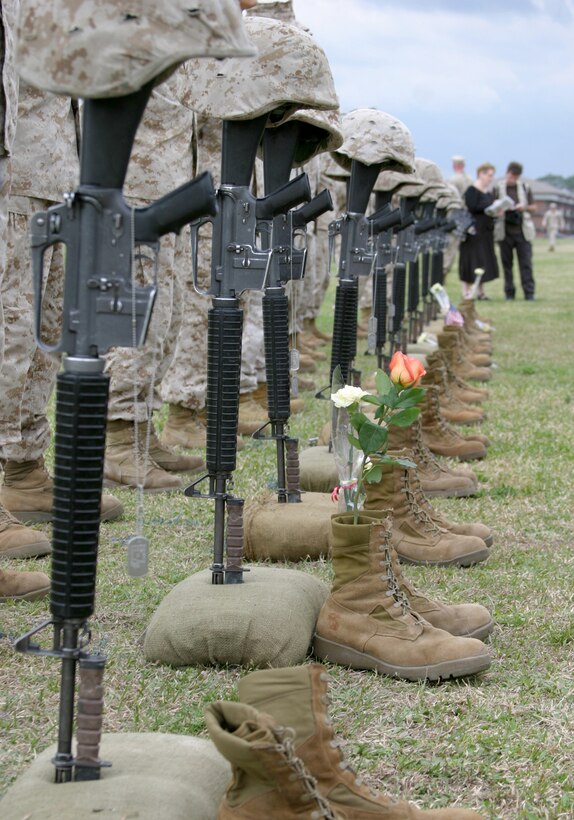 Marines of the 24th Marine Expeditionary Unit stand behind memorial displays for their fallen comrades as families place flowers and flags beside the displays to honor the Marines lost during the MEU’s tour of Iraq in support of Operation Iraqi Freedom II. The memorial took place at W.P.T. Hill Field, Camp Lejeune, N.C.