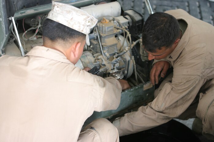 CAMP TAQADDUM, Iraq (May 2, 2005) – Lance Cpls. Willan D. Aguasurgiles, a Belleville, N.J., native,(left) and Mario C. Figueroa, a Brooklyn native, change the oil in one of the many generators here May 2.  The Marines of the utilities platoon, Support Company, 8th Engineer Support Battalion, 2d Force Service Support Group (Forward), are responsible for the maintenance of the generators, flood lights and mobile electrical power distribution systems that keep the base up and running.